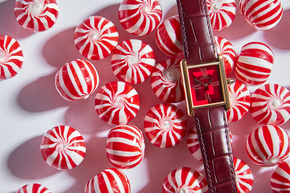 Red Cartier leather watch with round peppermint hard candies in the background